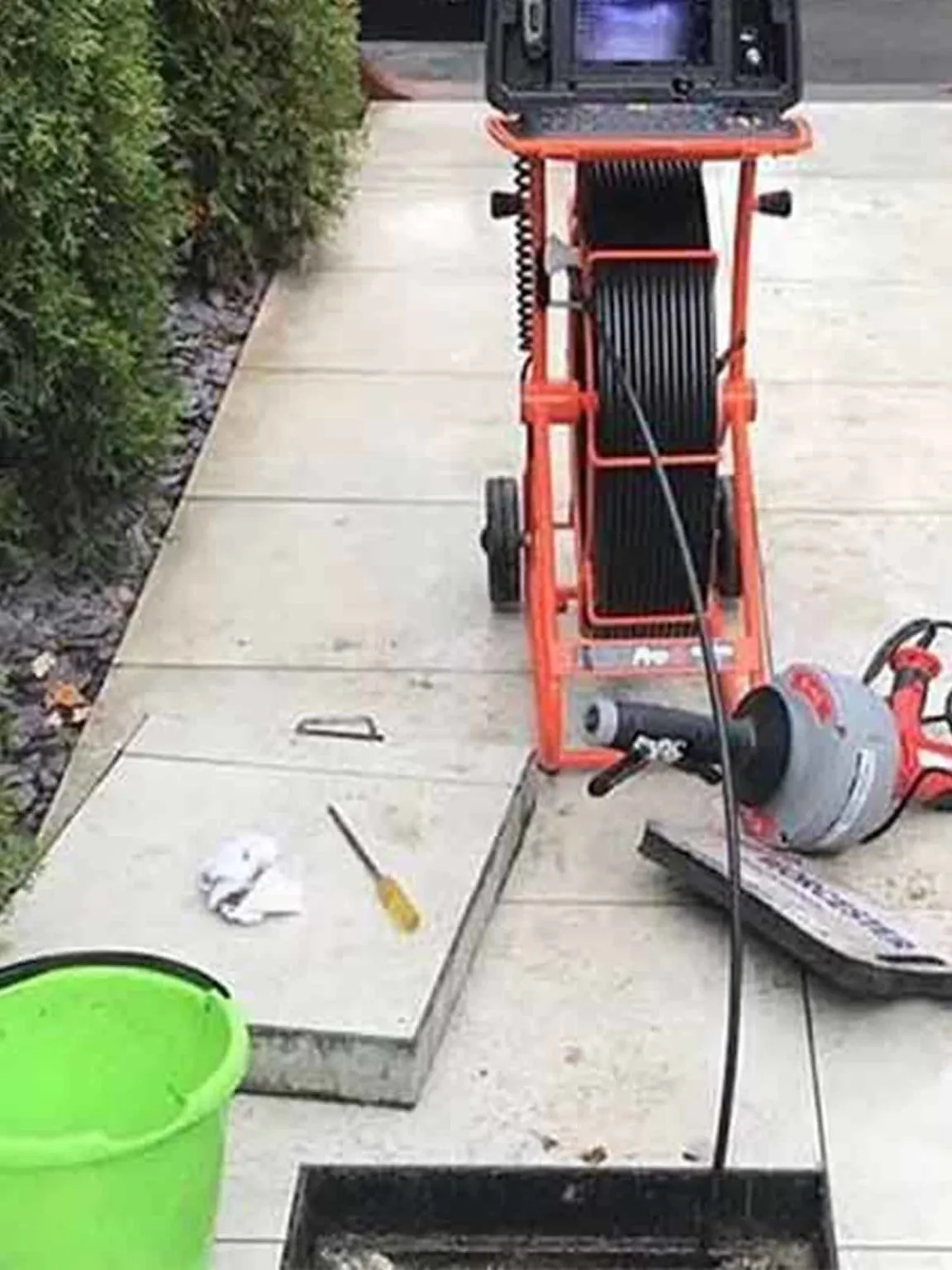 CCTV monitor and camera reel cart set up on a paved driveway, with no one in shot