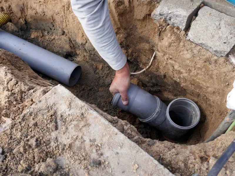 Hand joining a grey plastic pipe coupling in a trench, Derby DE23