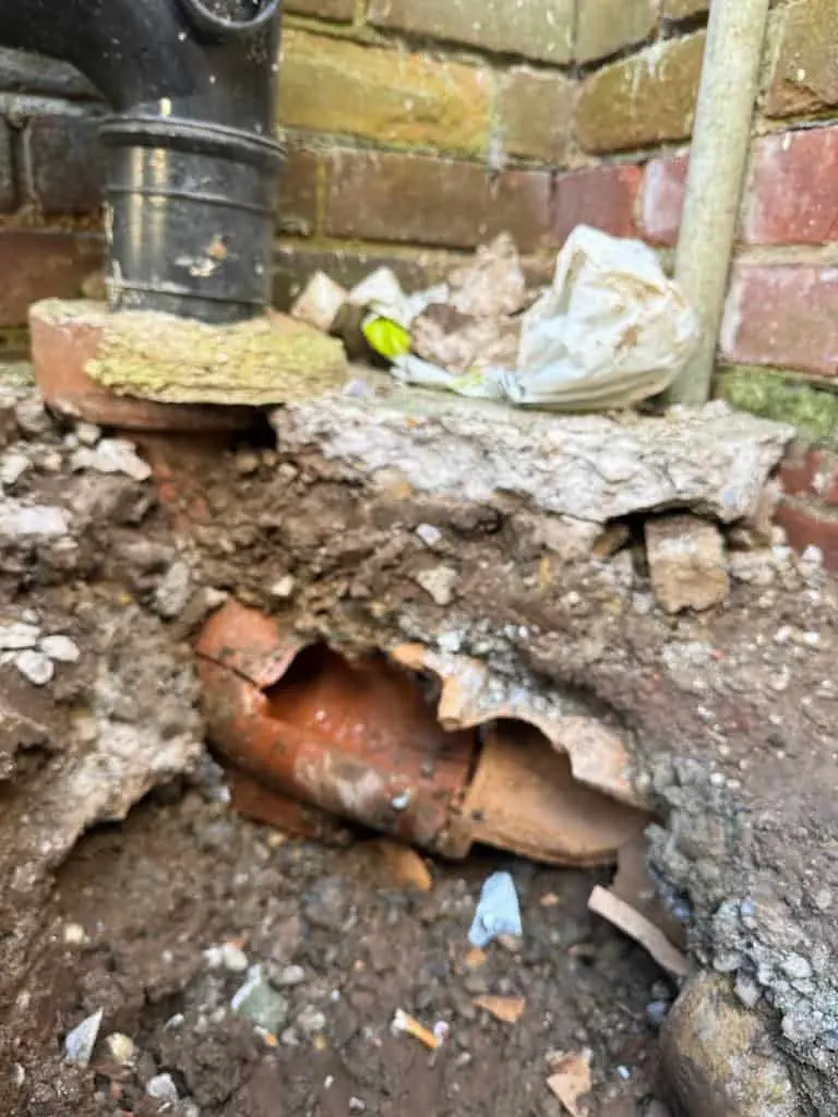Broken clay pipe joint exposed against a brick wall, Alvaston DE24